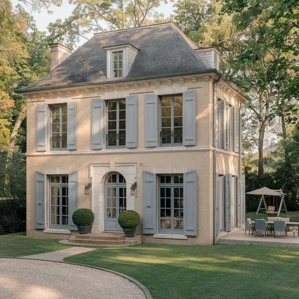 Pale stone villa with grey shutters on a lawn